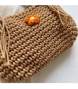 Detailed close-up of handmade woven rope texture with a small yellow crochet flower