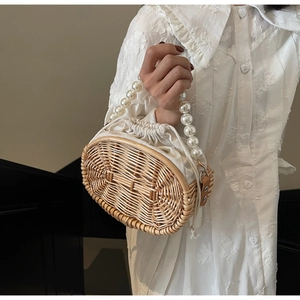 Detail of woven rattan handbag featuring faux pearl handle and white drawstring liner
