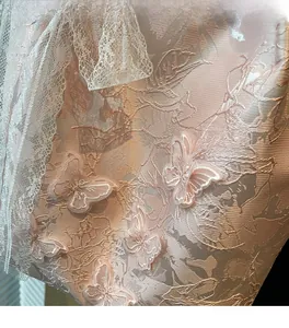 Dettaglio del tessuto jacquard rosa con farfalle ricamate in 3D e bordo in pizzo bianco