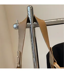Détail de la bandoulière en cuir marron avec coutures apparentes et rivets métalliques