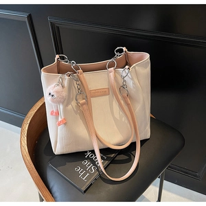 Detail of cream tote bag with pink leather chain strap and cute monster fur ball charm