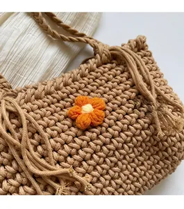 Detail of hand-woven beige basket bag featuring a vibrant 3D orange knit flower