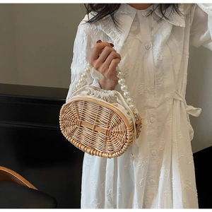 Detailed close-up of woven straw bag with elegant pearl handle and inner drawstring