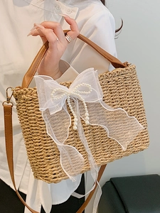 Chic summer straw tote bag featuring a white lace bow with pearl tassels and leather straps