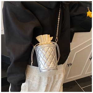 Detail of silver quilted bucket bag featuring a beige drawstring closure and gold chain