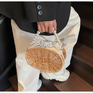 Detail of woven straw bag with elegant large pearl handle and white drawstring liner
