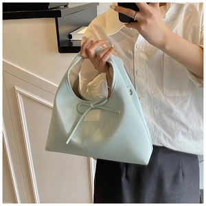 Detail of light mint green PU leather handbag featuring a bow and adjustable D-ring