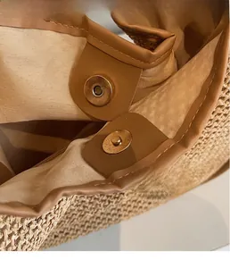Détail de la fermeture magnétique dorée d'un sac cabas en paille avec base en cuir