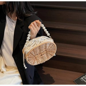 Detail of hand-woven straw bag with elegant large pearl handle and white drawstring liner