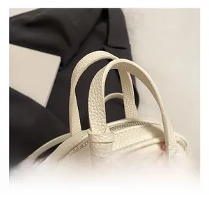 Close-up of white lychee pattern leather handbag showing soft dual handles and metal zipper