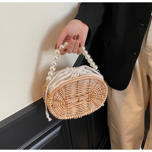 Detail of woven rattan handbag with elegant large pearl handle and drawstring lining