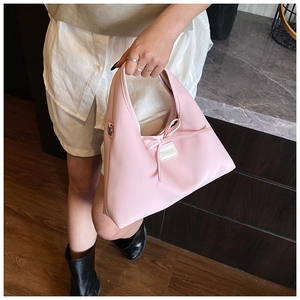 Detail of light pink dumpling bag with bow decoration and white COCO label
