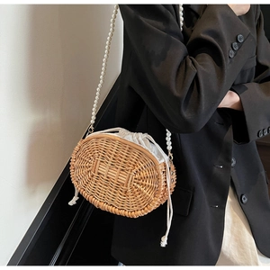 Detail of woven straw bag showing pearl strap and drawstring liner for summer beach vacation