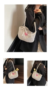 Detail of hand-woven cream tote featuring a pink knit flower and chic tassel accents