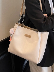 Minimalist beige tote bag with brown leather straps and pink plush monster charm