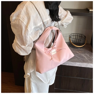 Detail of light pink shoulder bag with soft knot design and stylish silver chain strap