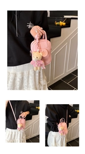 Detailed view of a pink pebbled leather mini crossbody bag with cute teddy bear charm