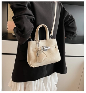 Detail of cream lychee leather bucket bag with silver twist lock and heart charm pendant