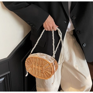 Detailed close-up of woven rattan bag featuring elegant white pearl bead handle and linen liner