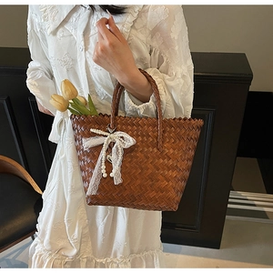 Détail du panier tressé marron foncé avec nœud en dentelle blanche et pompon de perles