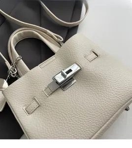 Detail of lychee textured leather and silver metal twist lock on cream bucket bag