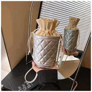 Detail of silver quilted bucket bag with beige drawstring and gold chain strap