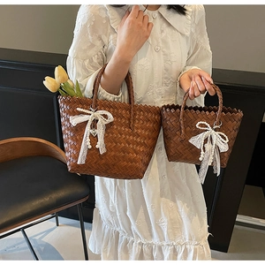 Détail de sacs fourre-tout en paille avec nœuds en dentelle blanche et perles pour les vacances