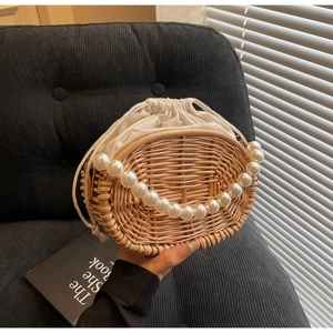 Close-up of woven rattan bag featuring elegant large pearl handle and canvas drawstring lining