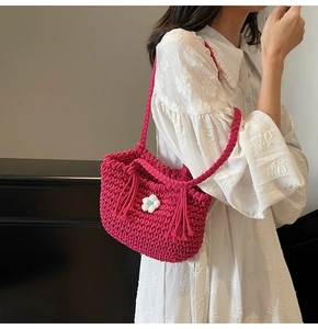 Detail of magenta crochet woven bucket bag featuring small blue and white flower accent