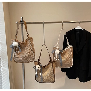 Détail de sacs fourre-tout en paille tissée de diverses couleurs avec nœuds et pompons