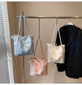 Dettaglio delle borse tote con ricamo a farfalla nei colori blu, rosa e bianco