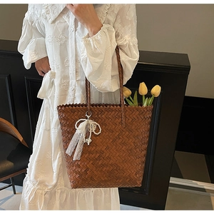 Détail d'un sac cabas en paille tissé main avec dentelle élégante et nœud en perles