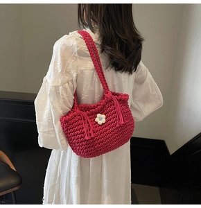Detail of rose red hand-woven shoulder bag with white knit daisy and trendy tassels