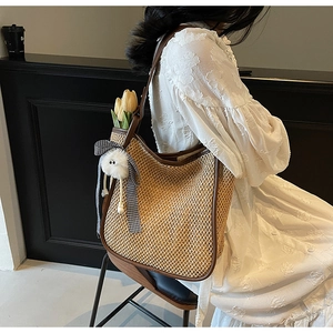 Détail du sac cabas évidé en paille avec bordure en cuir marron et breloque en peluche
