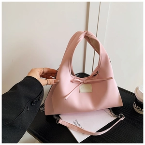 Detailed close-up of a pink bow dumpling bag with a metal chain and branded leather patch