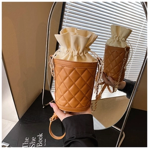 Close-up of caramel quilted bucket bag with drawstring canvas insert and chain strap