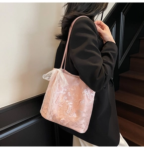 Dettaglio della borsa tote in pizzo rosa con fiocco elegante indossata da una modella