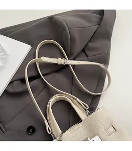 Detail of cream lychee texture leather bucket bag with silver hardware on suit fabric