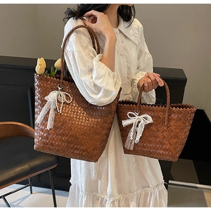 Détail des sacs cabas en paille marron avec décoration nœud en dentelle et perles