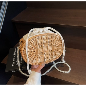 Detailed macro of vintage woven straw bag with faux pearl strap on wooden steps