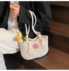 Detailed close-up of white chunky knit crochet basket bag with pink floral decoration