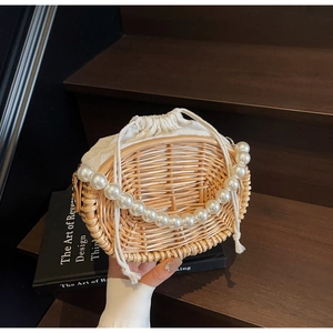 Detail view of woven straw bag with elegant pearl handle and white drawstring liner