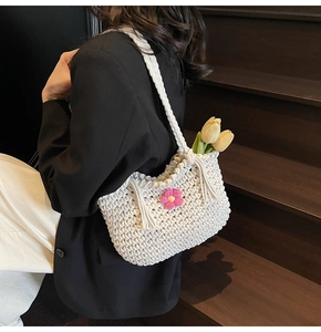 Close-up of white woven tote bag with pink crochet flowers and fringe details