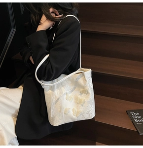 Dettaglio borsa tote in pizzo bianco con farfalle 3D e trama floreale dal design raffinato