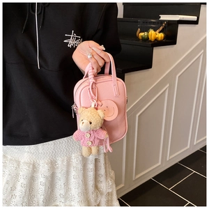Detail of pink lychee leather mini crossbody bag with embossed smiley and teddy bear charm