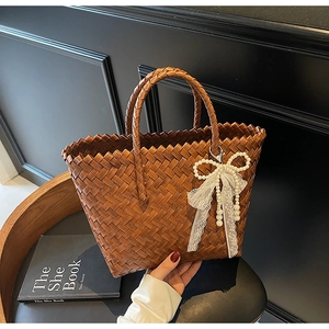 Détails du tissage en cuir marron avec nœud en dentelle et perles sur le sac