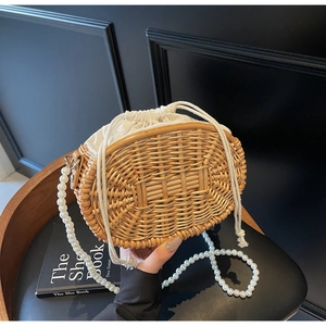 Detailed close-up of handmade straw bag with pearl strap and drawstring inner liner