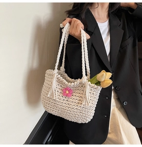 Detail of hand-woven cream tote with pink flower detail worn by model in black suit