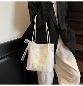 Dettaglio della borsa tote in pizzo bianco con farfalle ricamate 3D e nastri a fiocco
