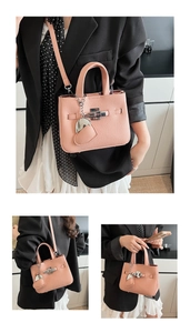 Detail of pink lychee leather bucket bag with silver cross lock and heart charm accessory